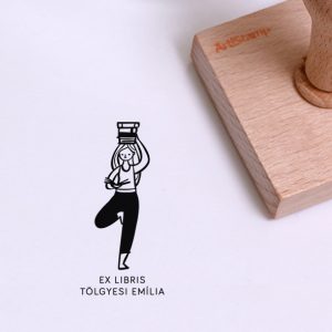 Ex libris pecsét, jógás fa állásban olvasó lány, a fején könyveket tartva ábrázoló grafikával. Nyeles fa alapra készült, gumi lenyomattal, egyedileg megadott névvel készült.