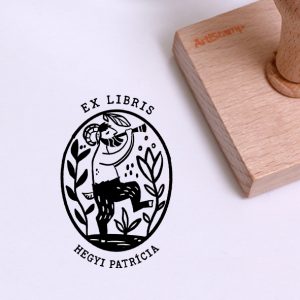 Ex libris pecsét, pánsípon játszó, táncoló pán, növények között ábrázoló grafikával. Nyeles fa alapra készült, gumi lenyomattal, egyedileg megadott névvel készült.