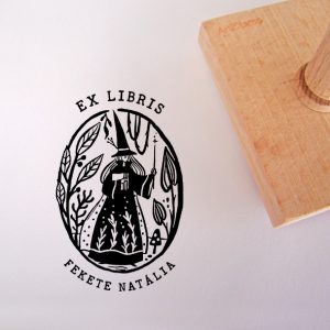 Ex libris pecsét, erdőben, könyvet magához ölelő varázsló, kezében varázspálcával ábrázoló grafikával. Nyeles fa alapra készült, gumi lenyomattal, egyedileg megadott névvel készült.